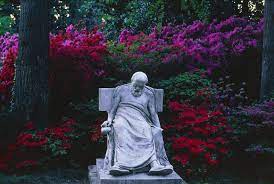گل‌های قرمز و بنفش پر جنب و جوش در پشت مجسمه مردی که به زمین افتاده است.